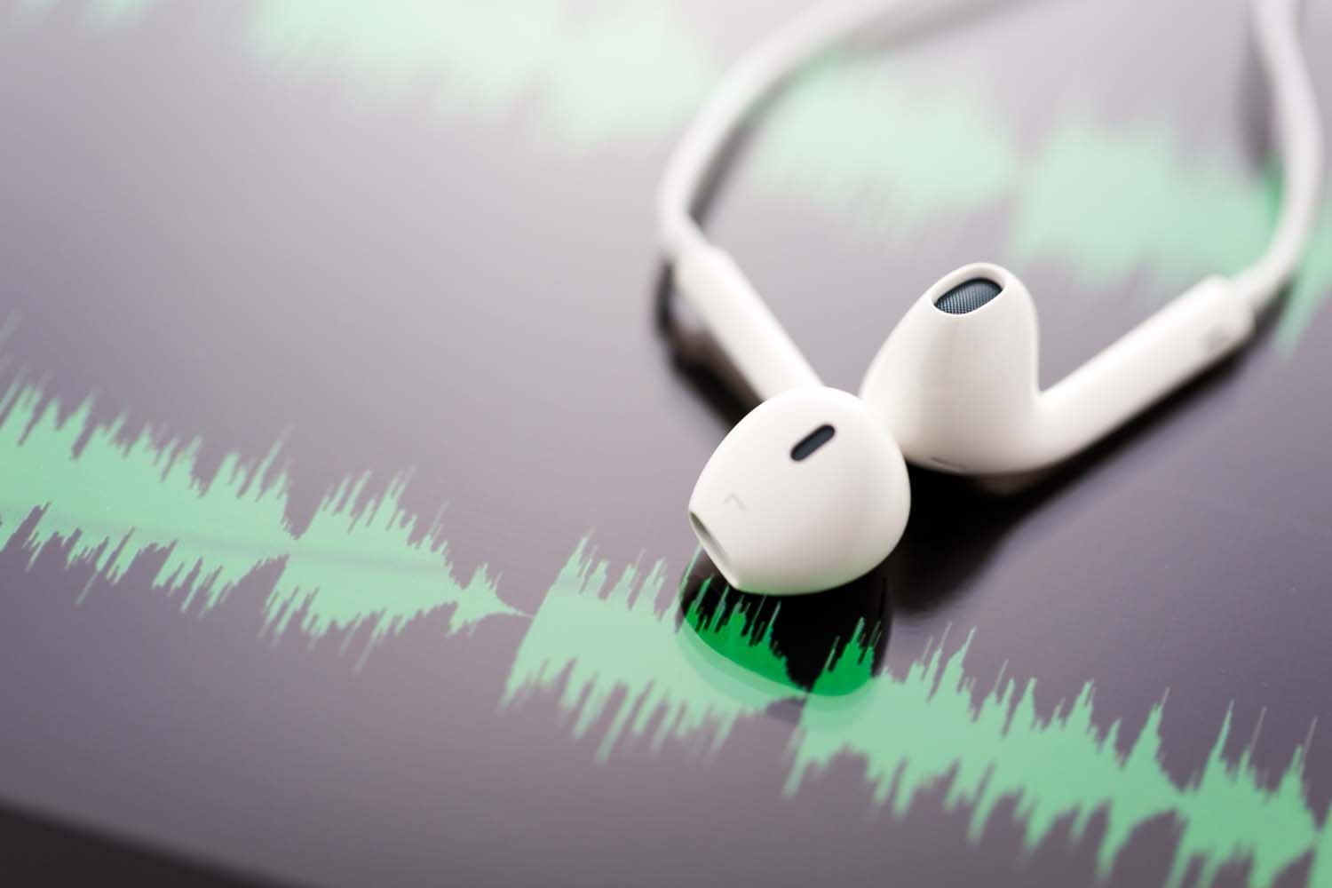 Audio Headphones lying on an image of an audio waveform
